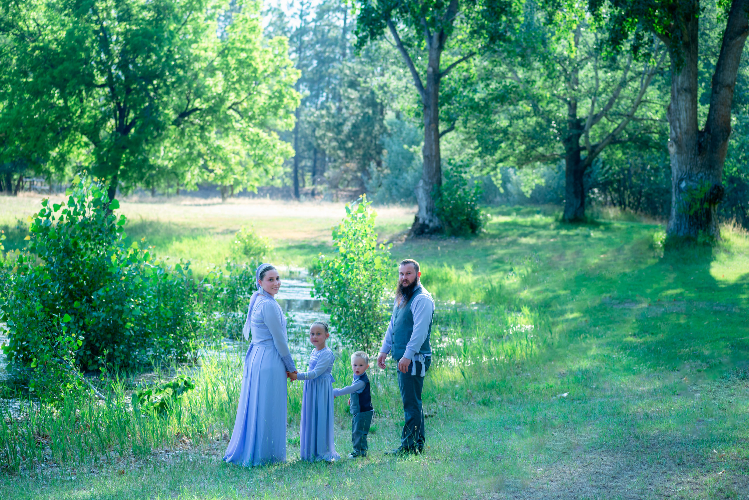 family of 4 walking through a park holding hands spas in spokane