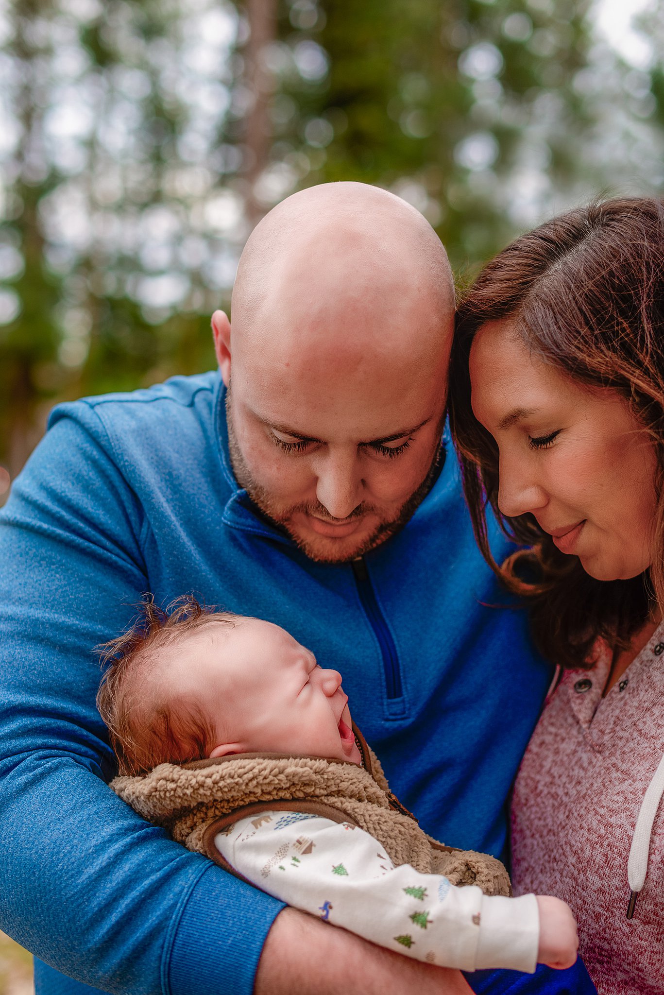 mom and dad looking at their newborn baby in a forest Spokane Midwives