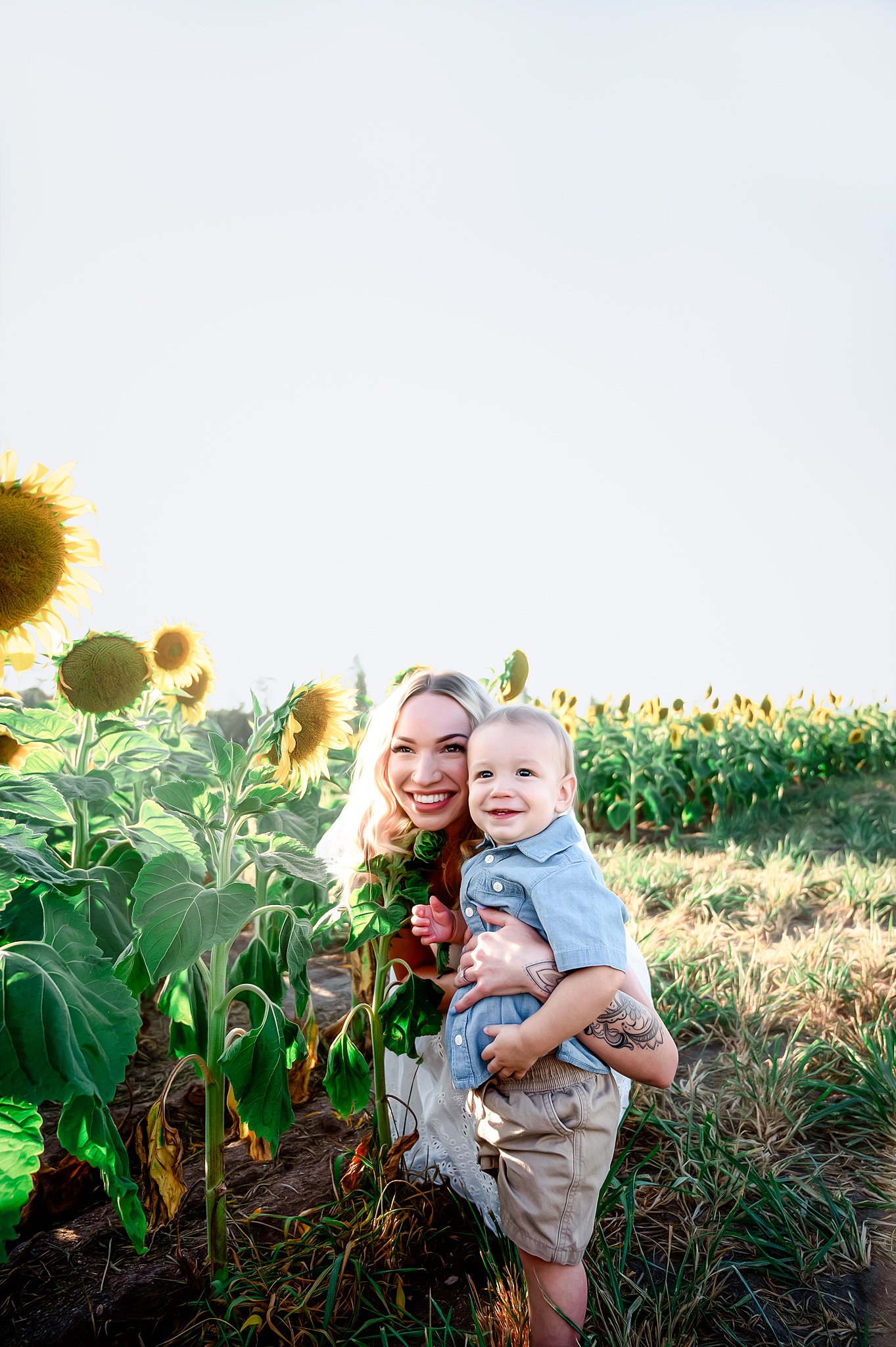 mom and her young son laughing in a sunflower field