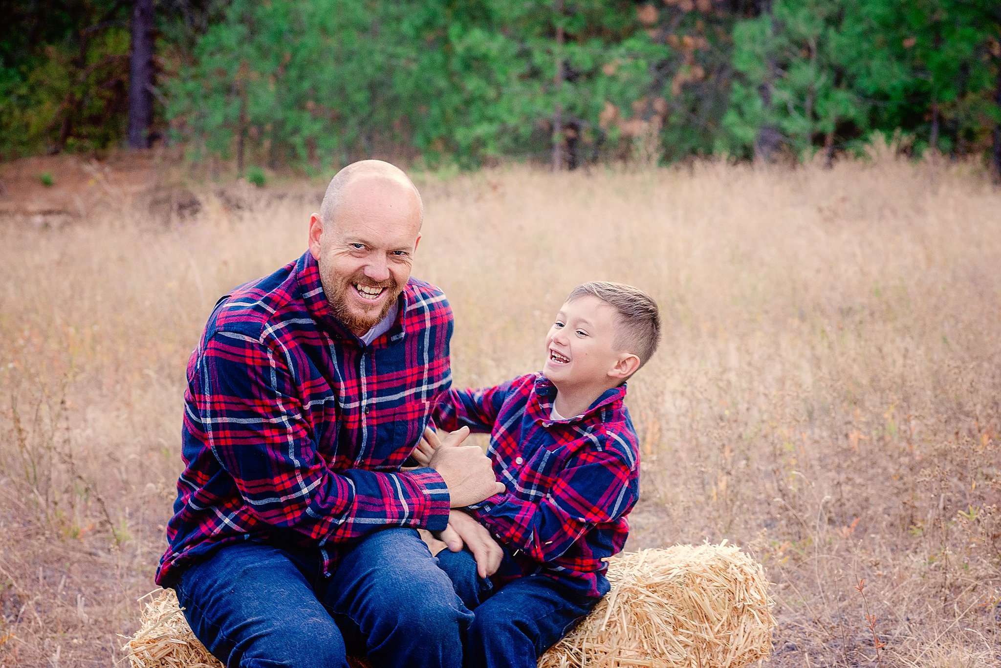 dad and son laughing and playing on a hay bale Spokane Toy Stores