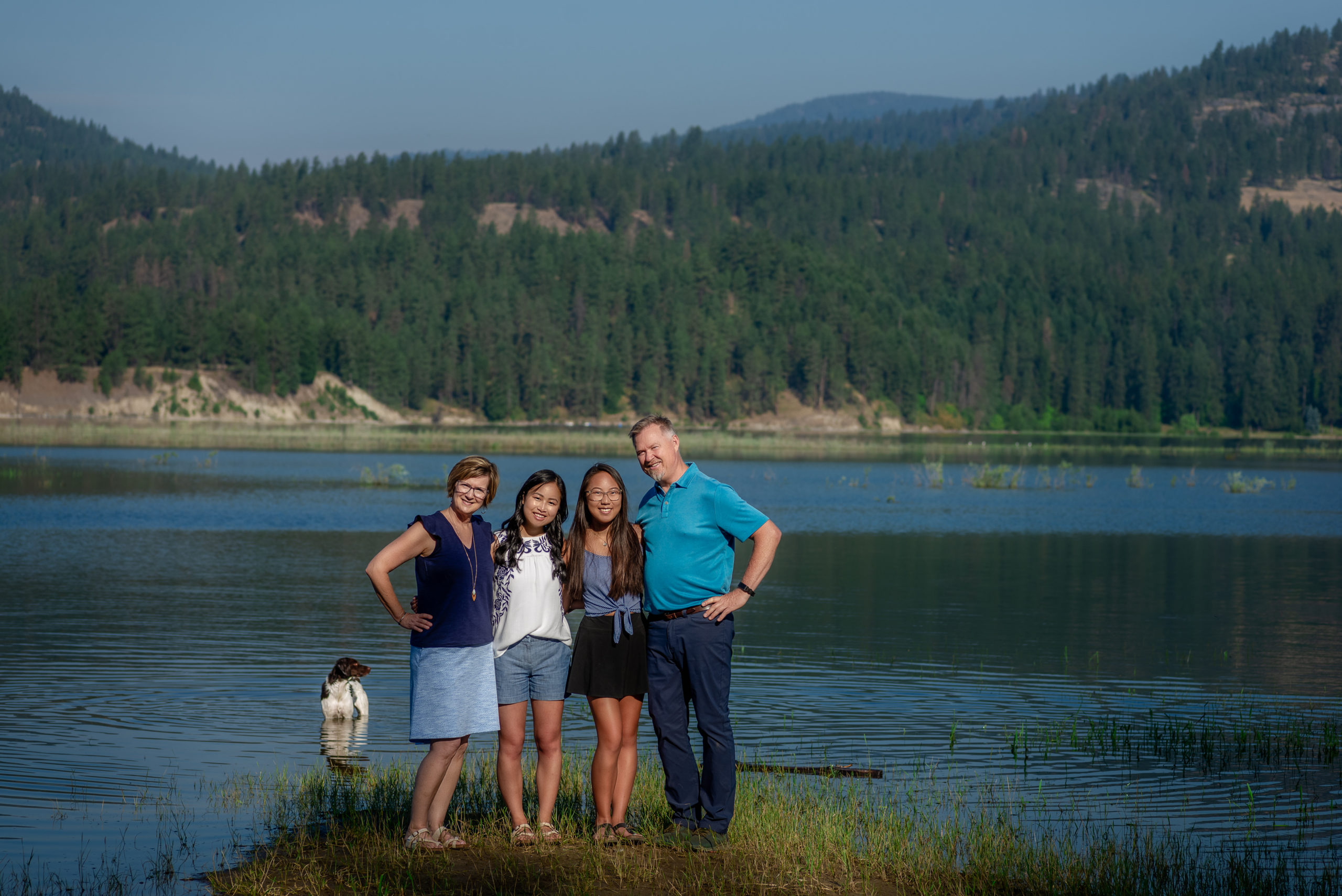 family of 4 and their dog standing near a lake near spokane pediatric dentist