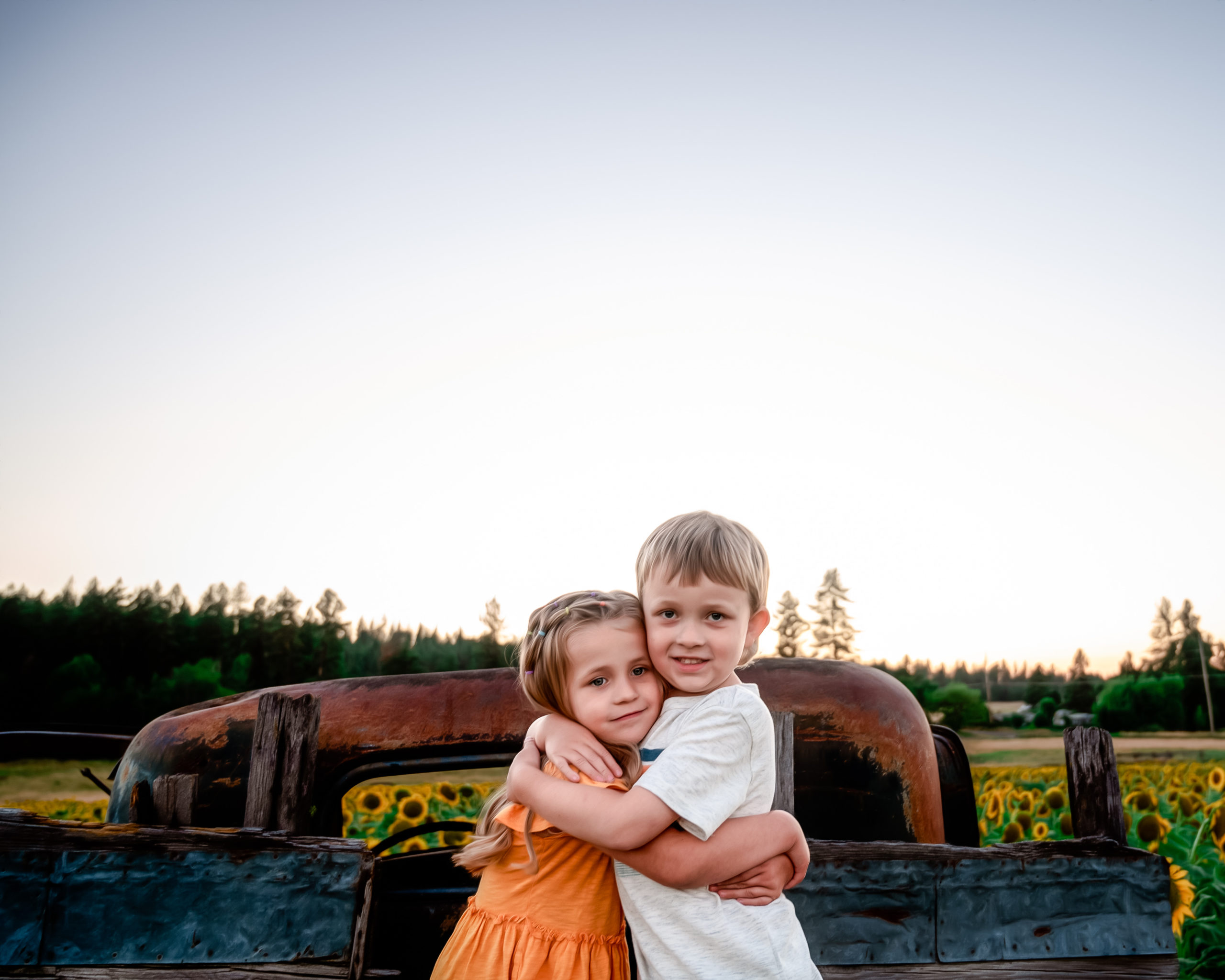 brother and sister hugging on the back of a truck