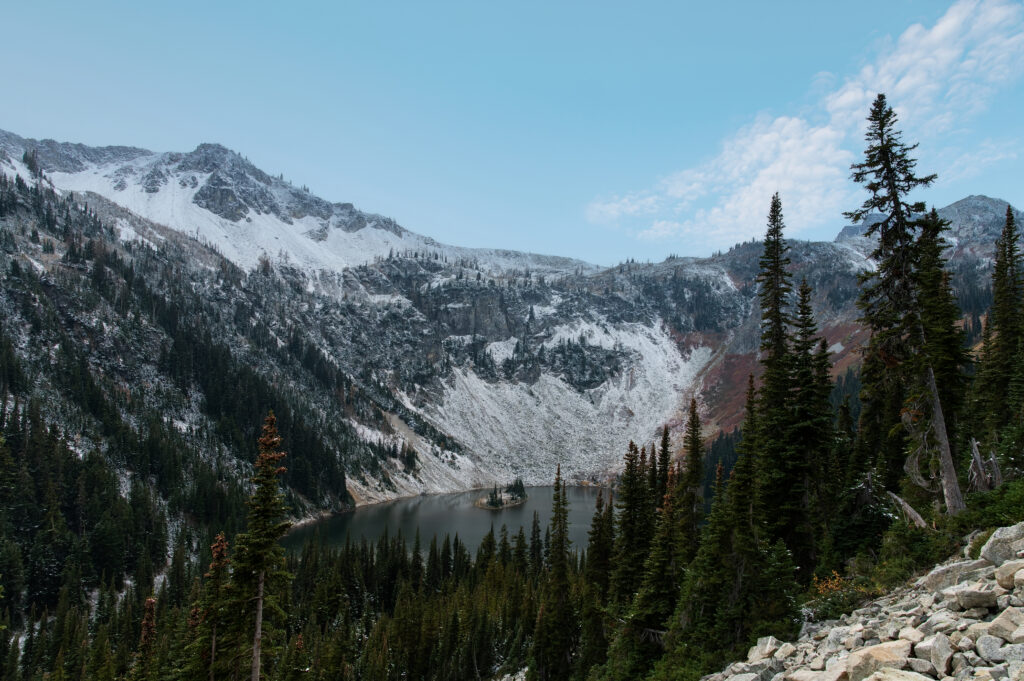 Alpine lake surrounded by evergreens and snow‑covered peaks in the North Cascades, photographed in a natural, storytelling style by a Washington family and headshot photographer.